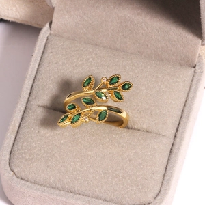 Macro d'une bague feuille dorée ornée de pierres marquises vertes dans un écrin