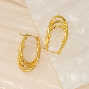 Detail shot of golden multi-layered oval earrings on marble texture surface