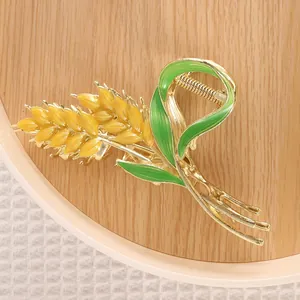 Close-up of a floral hair claw clip featuring golden wheat ears and green enamel leaves