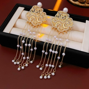 Detail of golden cloud motif earrings with sparkling diamonds and hanging pearl tassels