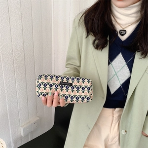 Close-up of a floral corduroy cosmetic bag with a merciparis label held by a hand