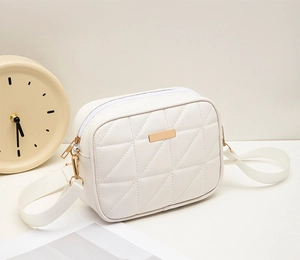 Detailed macro view of white quilted faux leather bag with elegant golden logo plate
