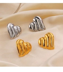 Détail des boucles d'oreilles en forme de cœur dorées et argentées sur fond de soie beige