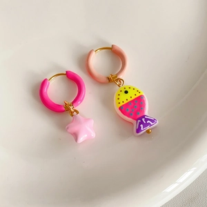 Detailed view of colorful asymmetric fish and star pendants on steel hoop earrings