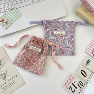 Deux pochettes à cordon en tissu floral rose et bleu sur un bureau de style minimaliste