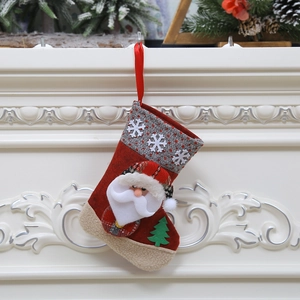 Chaussette de Noël avec peluche Père Noël et motifs tricotés suspendue à une cheminée