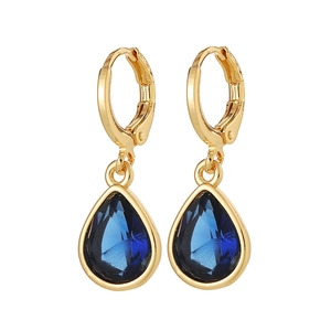 Close-up of teardrop earrings featuring faceted navy blue gemstones in golden settings