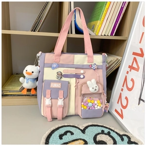 Detail of color-block canvas schoolbag with cute duck pendant and cartoon badges