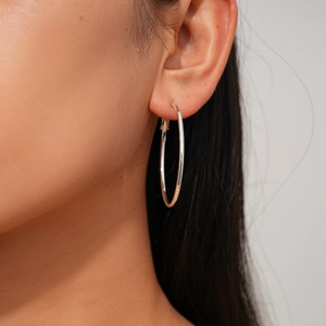 Close-up of a large silver hoop earring worn by a model to show size and polished finish