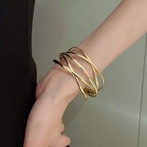 Close-up of golden multi-layer crisscross cuff bracelet on woman's wrist