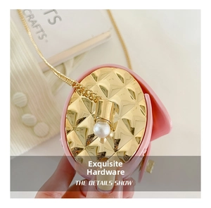 Detail of pink quilted handbag with gold metal hardware, chain strap and pearl charm