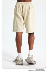 Detail of men's beige cotton shorts showing elastic waistband and back pocket texture