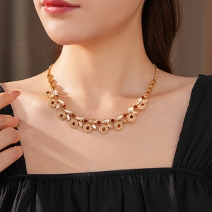 Close-up of vintage gold necklace with hollow circles and ruby red crystal stones
