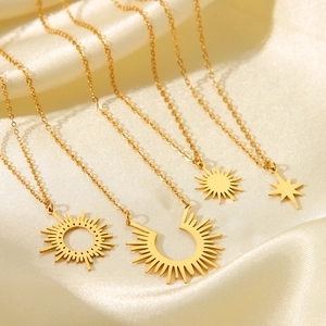 Five gold-plated stainless steel necklaces with sun and star pendants on champagne silk