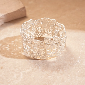 Detailed view of silver matte cuff bracelet with hollow floral cutouts on a stone base