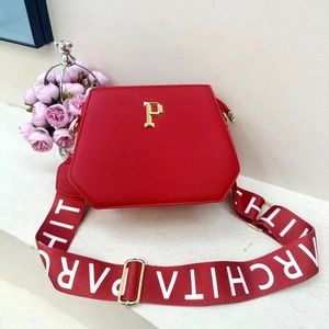 Macro shot of red textured PU leather tote bag with gold P emblem and wide strap