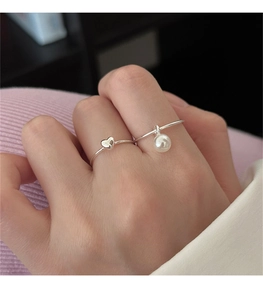 Close-up of 925 sterling silver rings featuring a heart charm and a single pearl pendant