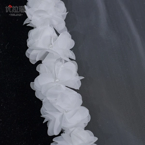 Detail of white 3D chiffon flowers with pearl accents on delicate bridal wedding veil