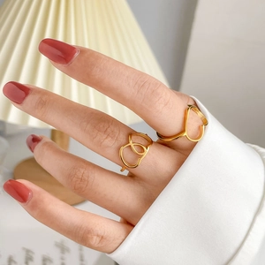 Golden heart-shaped cutout geometric rings worn by a model in a cozy lifestyle setting