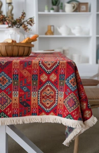 Macro view of heavy red ethnic jacquard tablecloth with intricate woven patterns and tassels