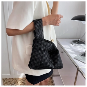 Close-up of black rhinestone knot handbag held by hand showing sparkly crystal texture