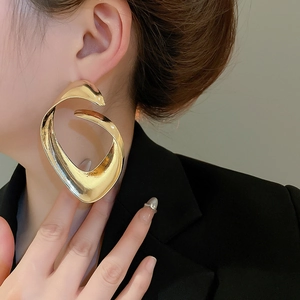 Primo piano di una modella con grandi orecchini a cerchio Mobius color oro lucido