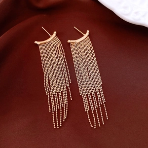 Macro detail of rose gold tassel earrings with fine bead chains on elegant silk fabric