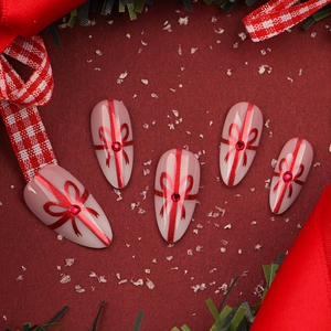 Faux ongles amande roses avec nœuds à paillettes rouges et strass pour les fêtes