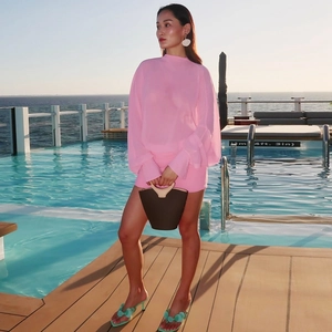 Detail of a bright pink chiffon two-piece set with long sleeves and a matching mini skirt