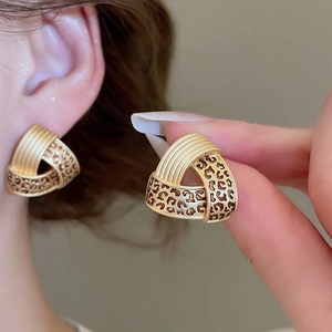 Detail view of gold geometric triangle stud earrings with brown leopard print texture