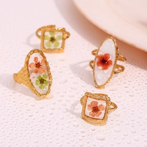 Detail of 18K gold-plated rings with dried flowers, resin and water drops on band