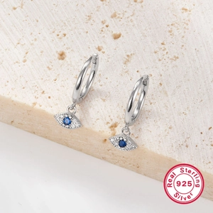 Close-up of S925 sterling silver earrings with blue zircon on beige stone surface