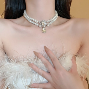 Detail of double-layer pearl necklace with teardrop pendant and diamond-encrusted accent