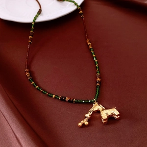 Detailed close-up of a golden horse pendant with green and brown beaded necklace chain