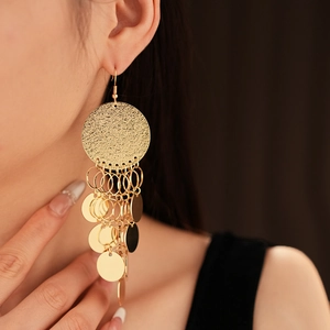Close-up of golden tassel earrings with textured round discs and dangling sequins
