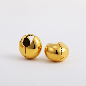Macro detail of high-polished 18K gold spherical earrings with mirror-like metallic finish