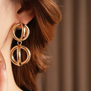 Minimalist gold hollow spherical drop earrings with interlocking circles on female model