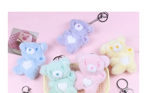 Macro shot of colorful plush teddy bear keychains with white heart details in a small basket