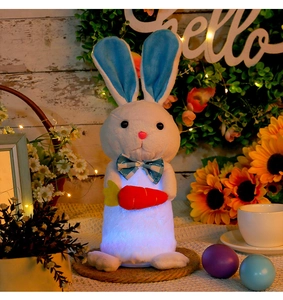 Close-up of glowing plush white bunny with blue ears and carrot for Easter decor