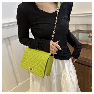 Detail of green quilted crossbody bag with gold chain strap and metallic lock closure