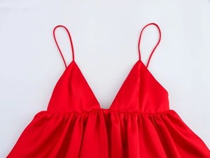 Détail d'un haut en satin rouge montrant le décolleté en V et les fines bretelles