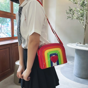 Close-up of rainbow crossbody bag in glossy patent leather with red heart and striped strap