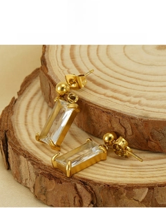 Detail view of 18K gold plated drop earrings with baguette cut zircon on wood surface