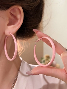 Detail showing high-quality pink enamel hoop earrings on ears and held in hand for size