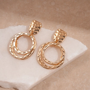 Détail macro de boucles d'oreilles à double anneau doré avec une texture martelée