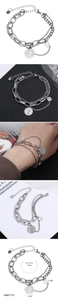 Detail of layered stainless steel bracelet featuring coin charms and lobster clasp