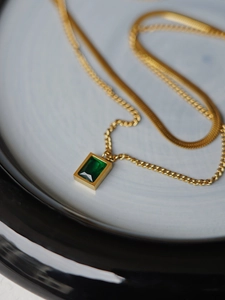 Close-up of double-layered gold snake chain with rectangular emerald green zircon pendant