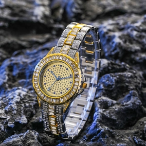 Luxury gold and silver two-tone quartz watch with full crystals on a rock surface