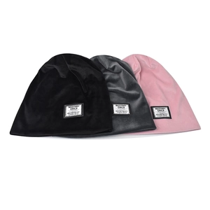 Detail view of colorful chenille knit beanies in black, pink, and grey with woven labels