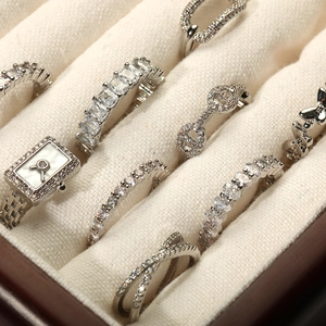 Détails de plusieurs bagues argentées avec zircons clairs dans un coffret à bijoux